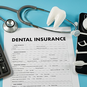 Dental insurance paperwork along with a calculator and dentistry instruments