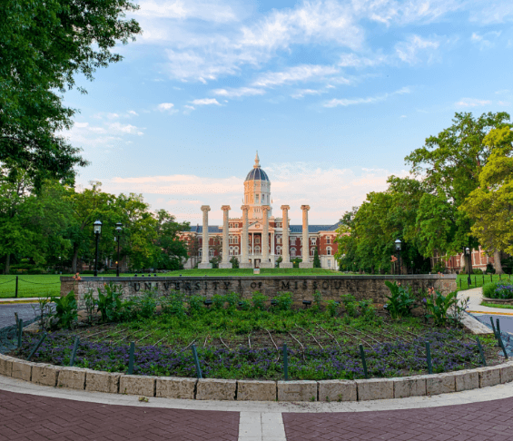 Outside of the a large university building with a prominent clock tower in the background